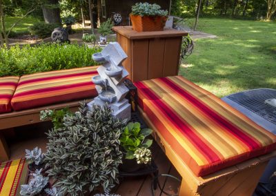 Striped multi-rust color cushion on a patio wood bench with