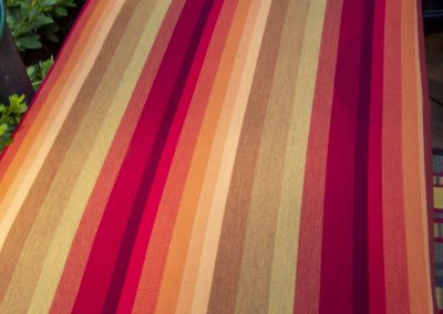 Closer view of striped multi-rust colored custom cushion on a patio wood bench